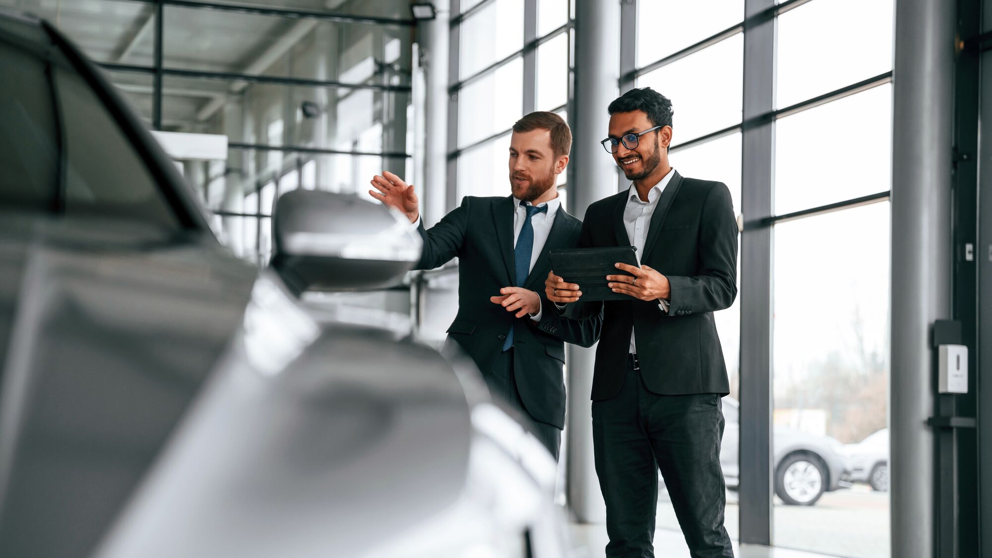 Looking at the vehicle. Man is consulting the customer in the car showroom