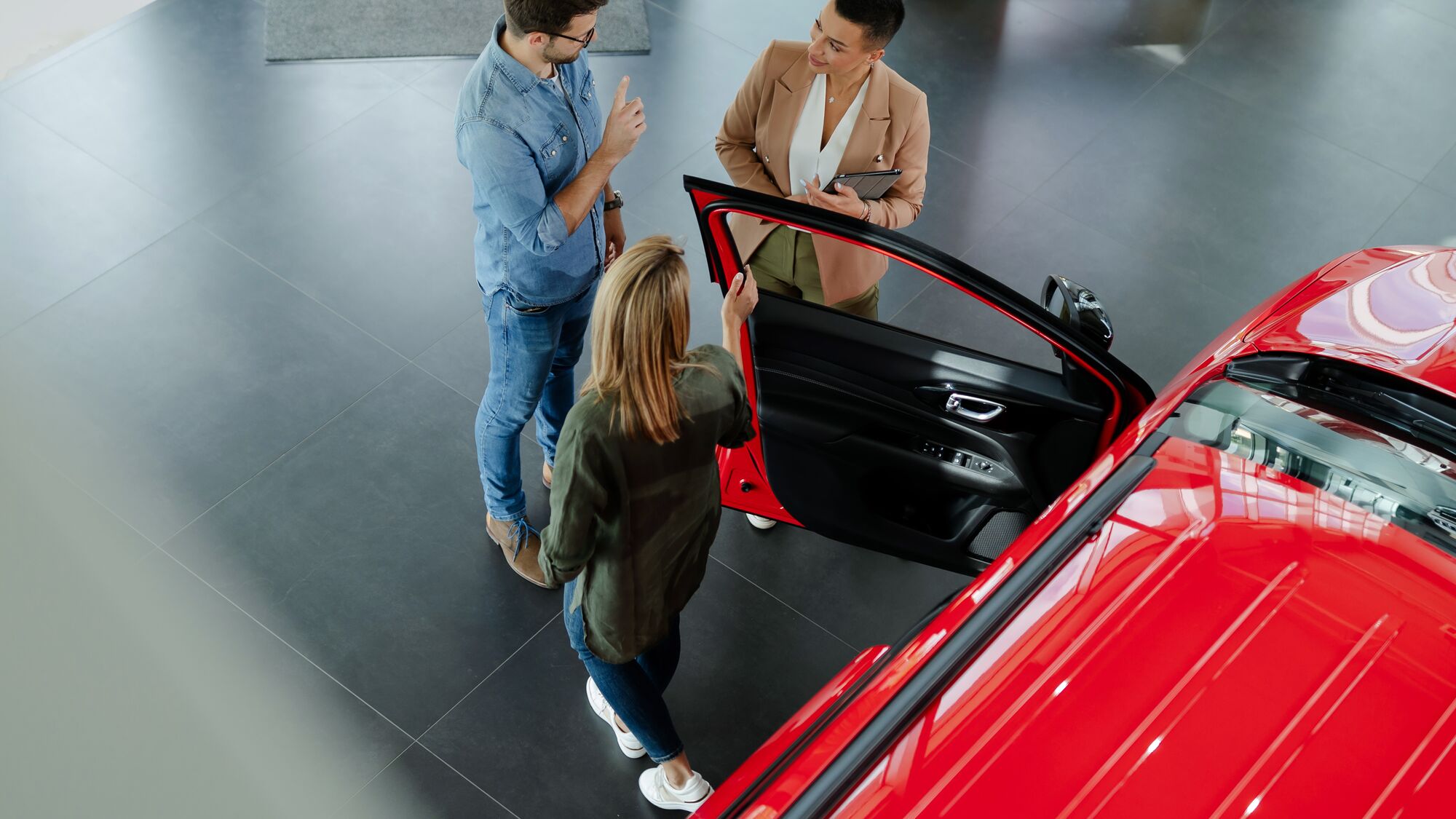 Top view of young couple choosing and trying new car in auto salon.