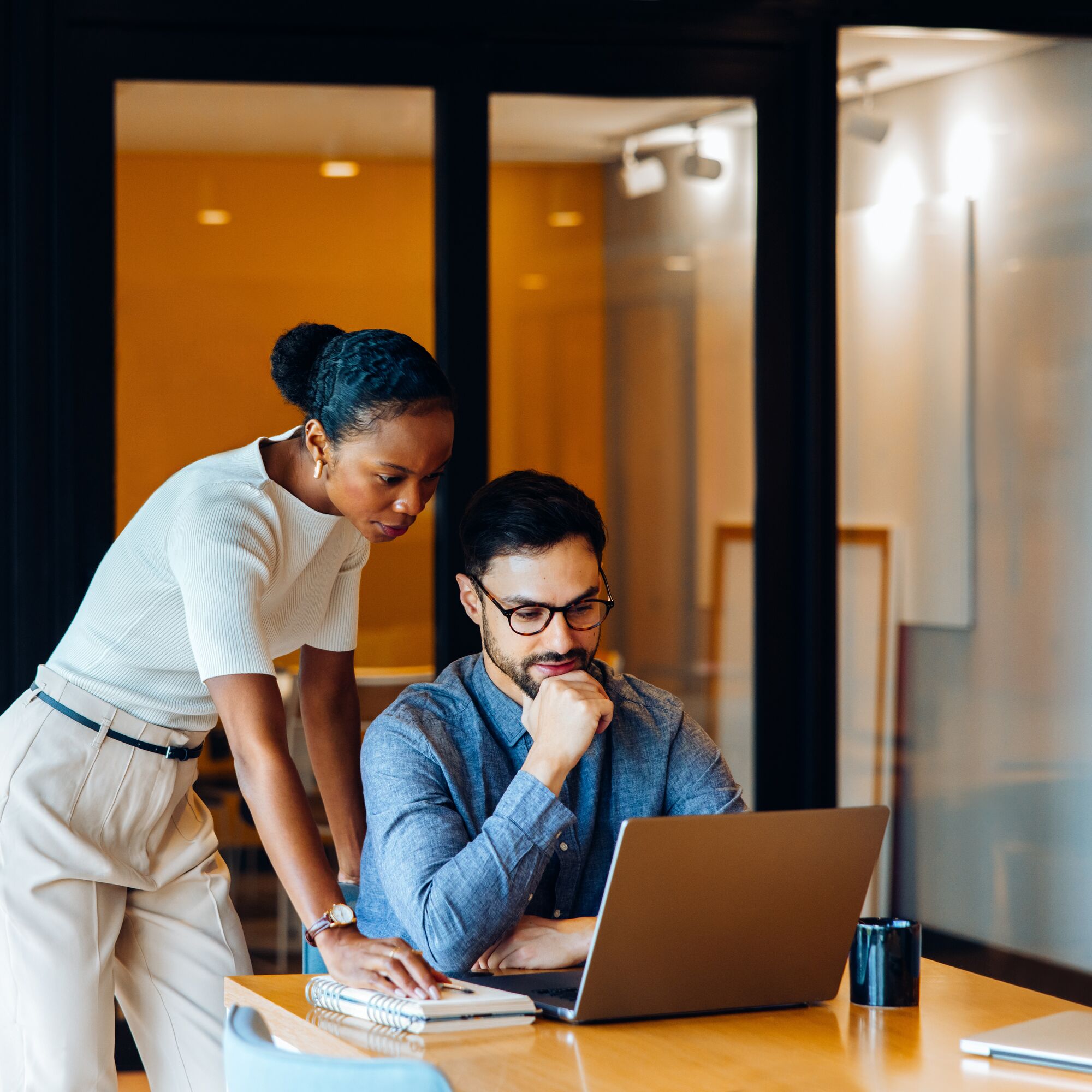 Two professionals analyzing data on a laptop in an office environment